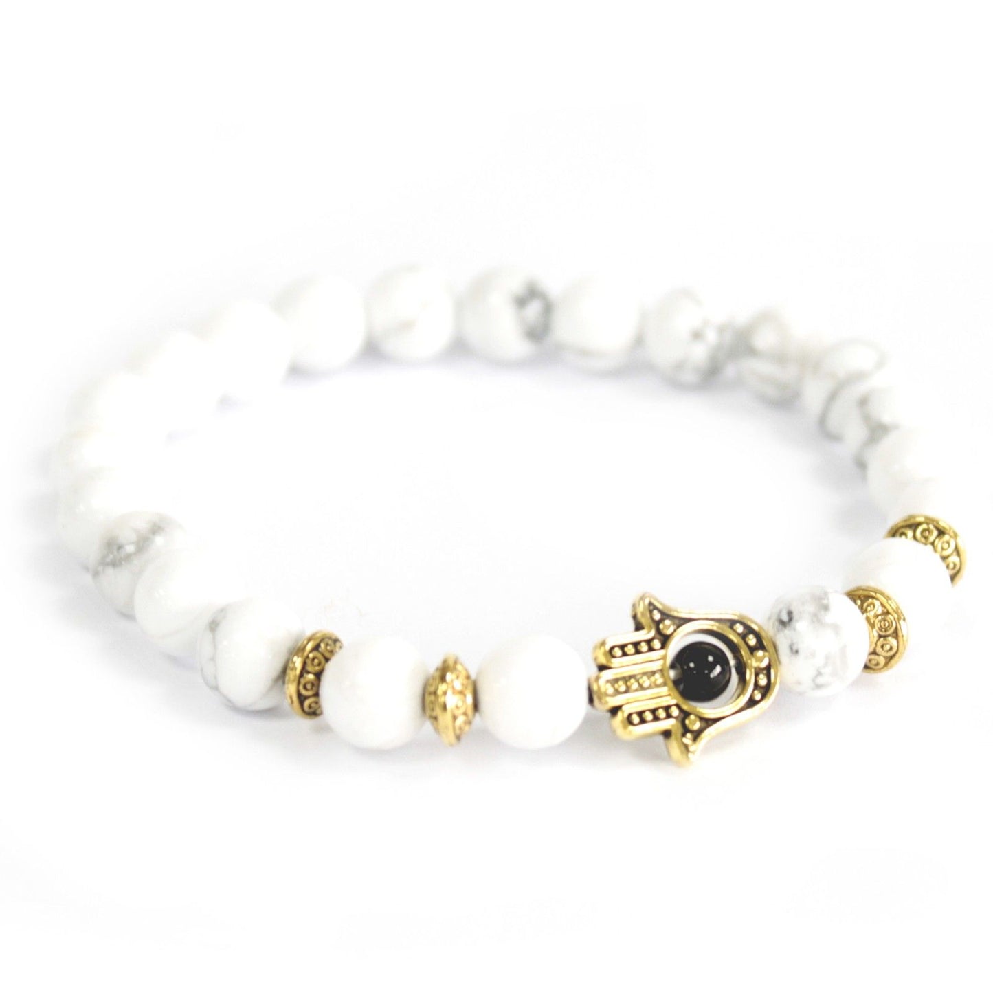 White beaded bracelet with gold and black hamsa hand charm on a white background