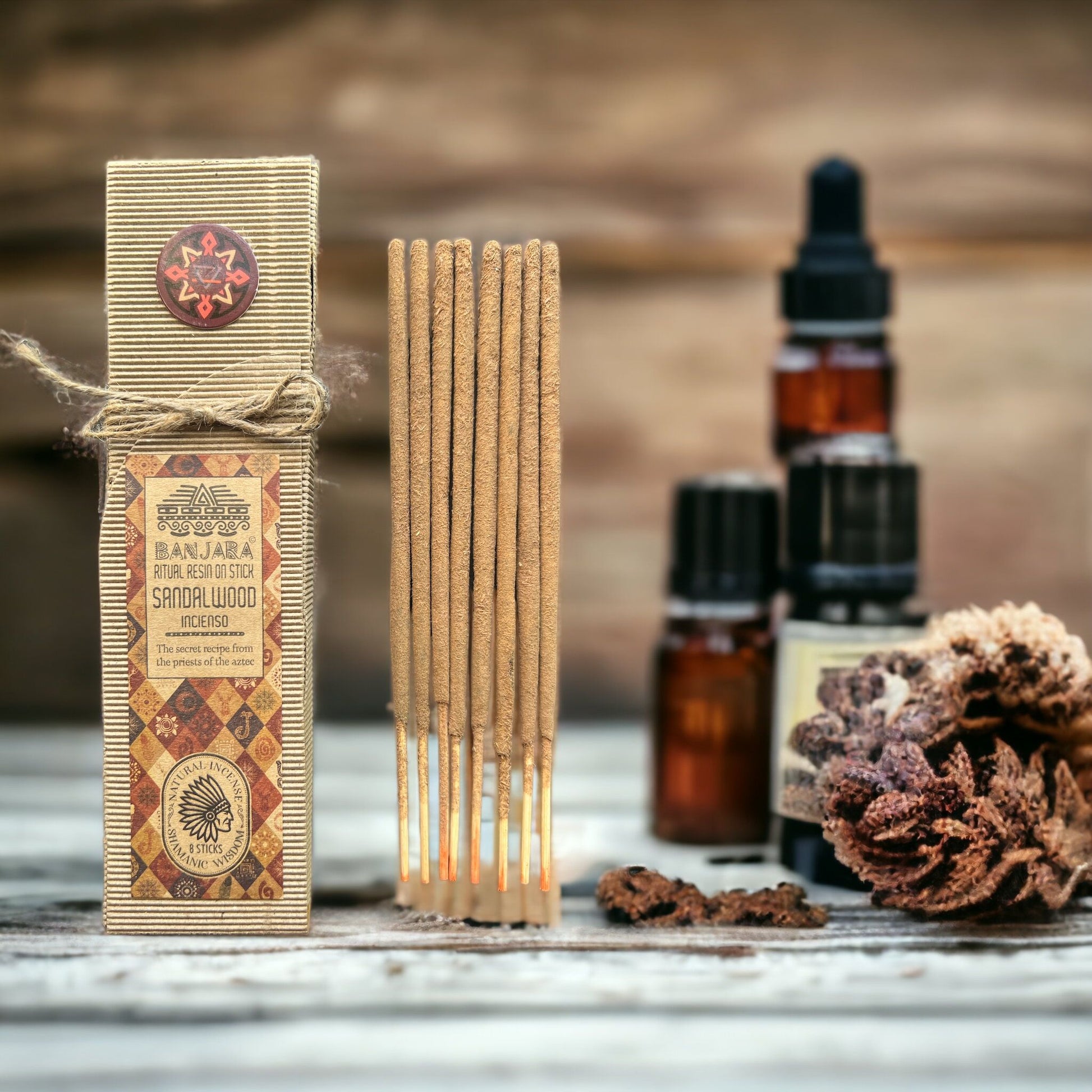 Incense sticks with packaging, essential oil bottles, and a pine cone on a wooden surface.